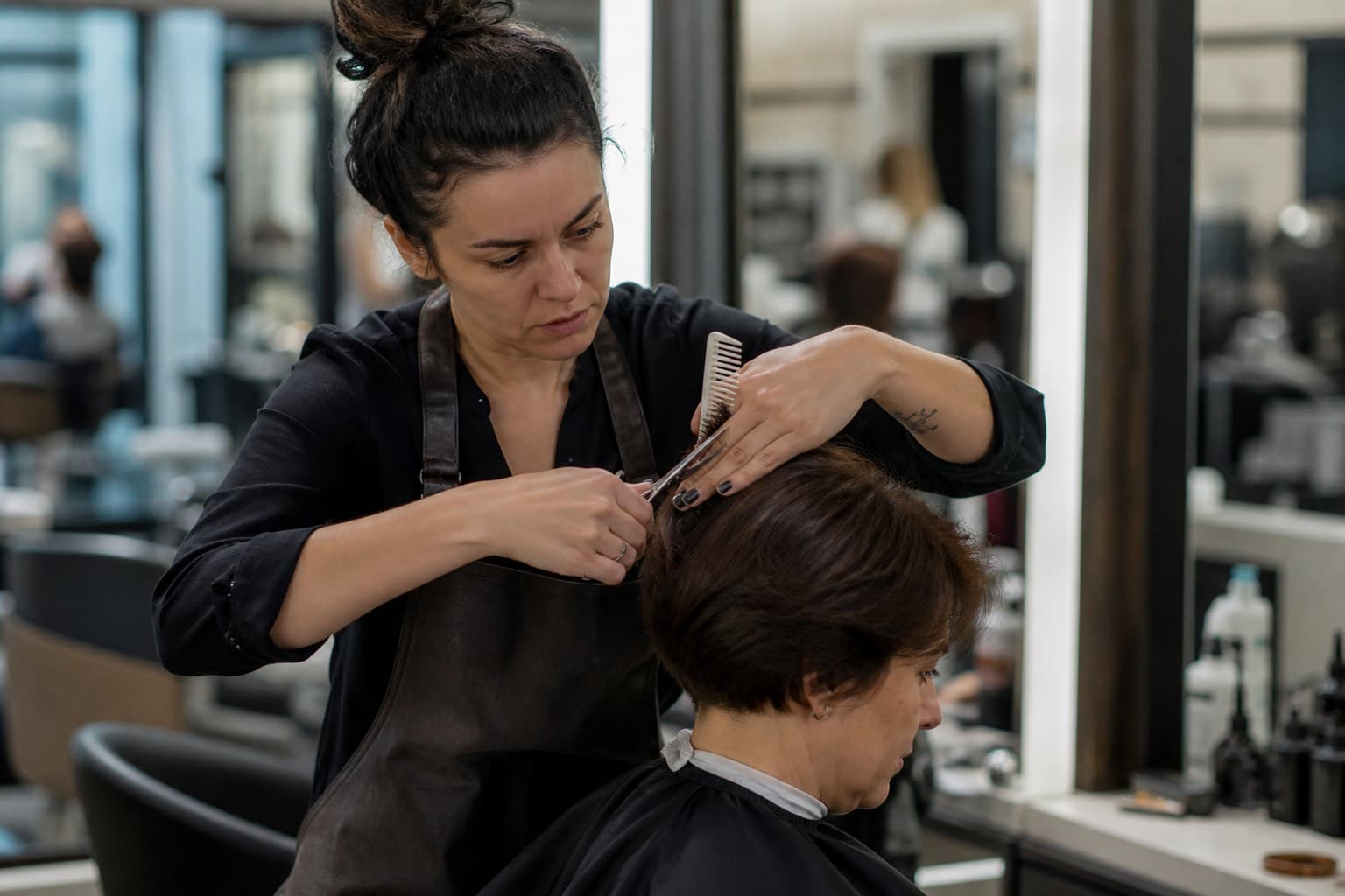 Stylist cutting a client’s hair, both hands occupied